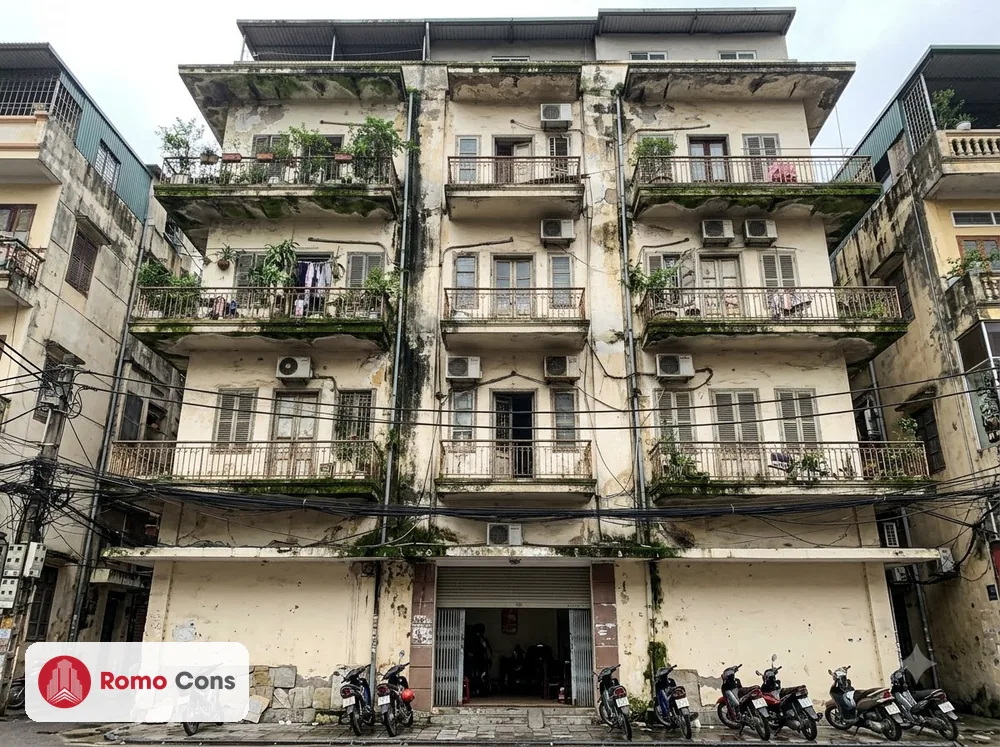 Mặt tiền tòa nhà cũ ở Hà Nội bị rêu mốc, loang ố dưới ban công và bong sơn