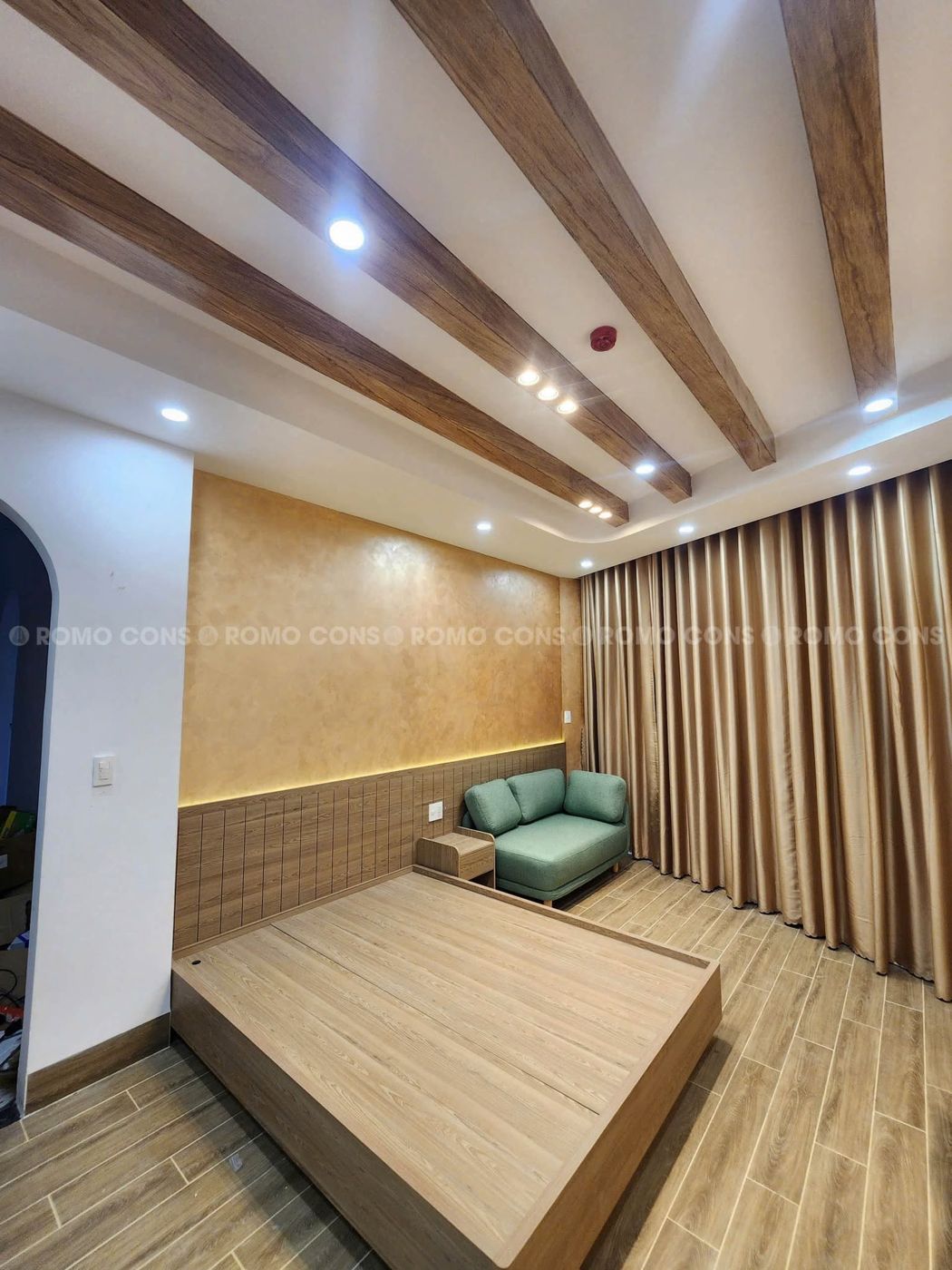 Căn hộ dịch vụ cao cấp tại KĐT Elysia Đà Nẵng 8 Phòng ngủ căn hộ dịch vụ Elysia với giường gỗ, sofa xanh và ốp gỗ đầu giường có đèn LED